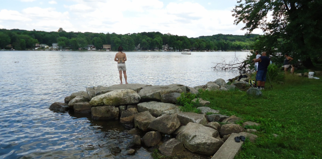 Woman fishing from a rocky lake shoreline
